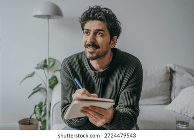 Handsome middle eastern looking man journaling or writing in a notebook