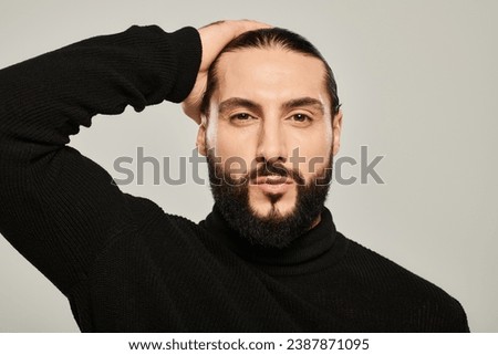 handsome middle eastern man in black turtleneck posing grey background, well-dressed and groomed