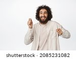 Handsome middle eastern man dancing and having fun, smiling and laughing, standing over white background