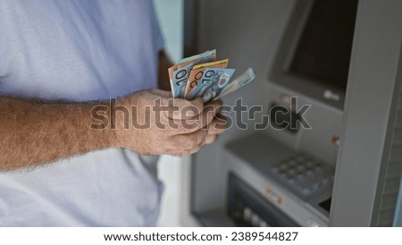 Handsome middle-aged caucasian man outside on urban street, captivating portrait of him holding wallet counting australian cash dollars at atm machine, engaging in banking transaction.