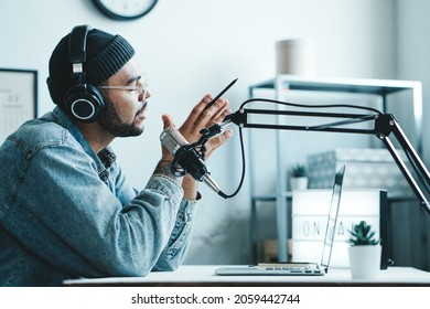 Handsome Mixed race content creator streaming his show at home studio using professional microphone and laptop, side view