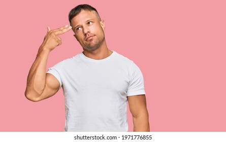 Handsome Muscle Man Wearing Casual White Tshirt Shooting And Killing Oneself Pointing Hand And Fingers To Head Like Gun, Suicide Gesture. 