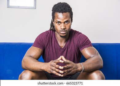 Handsome Muscular Black Man Sitting On Couch At Home, Looking Confident At Camera