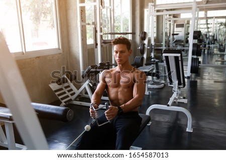 Handsome Muscular man doing exercise and pulling weights in seated cable row machine, Athlete makes exercise, Bodybuilder, Sport fitness and muscles concept