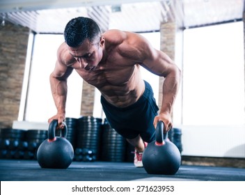 Handsome muscular man doing push ups on kettle ball in crossfit gym - Powered by Shutterstock