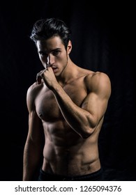 Handsome muscular shirtless young man standing confident, front view, looking at camera