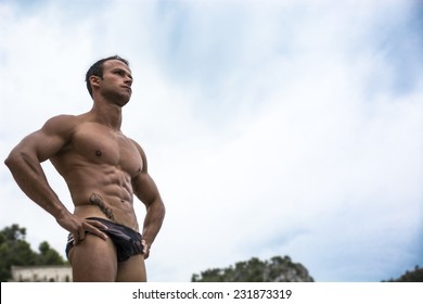 Handsome Muscular Young Man In Bathing Suit Shot From Below, Large Copyspace On The Sky