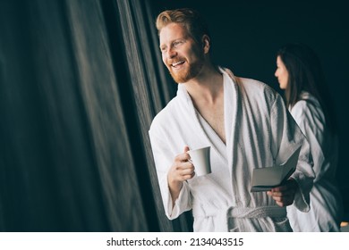 Handsome, muscular, young man drinking his morning coffee in a hotel room