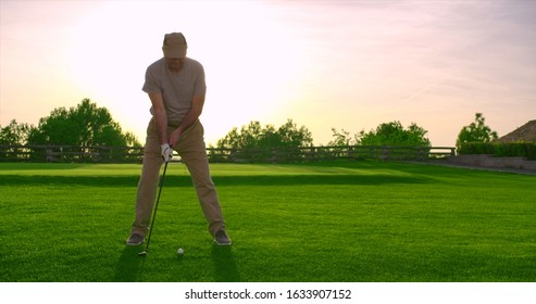 Handsome older golfer swinging and hitting golf ball on beautiful course at sunset. - Powered by Shutterstock