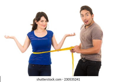 handsome open mouthed man holding measuring tape around thin fit young girl's stomach concept of dieting fitness weightloss  isolated on white