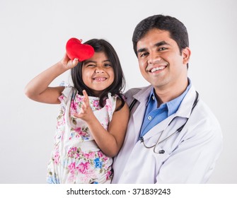 Handsome Paediatric Male Doctor Holding A Baby Girl Patient Holding Red Stuffed Heart Toy, Isolated Over White Background