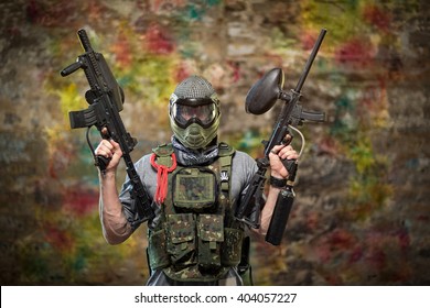 Handsome paintball gamer with guns in camouflage uniform 