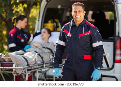 handsome paramedic with colleague and patient on background
