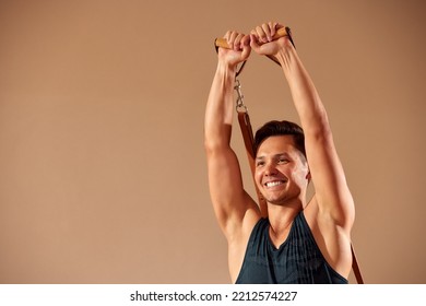 Handsome Pilates Male Instructor Performing Stretching Balance Fitness Exercise On Small Barrel Equipment, At The Pilates Studio Modern Onterior Indoor.