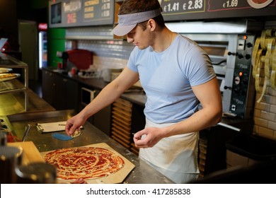 Handsome pizzaiolo making pizza at kitchen in pizzeria. - Powered by Shutterstock