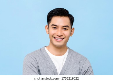 Handsome portrait of young Asian man smiling isolated on light blue background