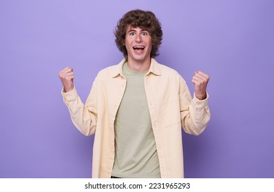 handsome positive happy young man isolated on purple background showing winner gesture. - Shutterstock ID 2231965293