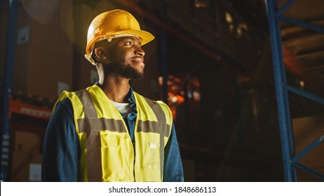 Handsome Professional Worker Wearing Safety Vest and Hard Hat Charmingly Smiling and Looks Into the Distance. In the Background Big Warehouse with Shelves full of Delivery Goods. Medium Portrait - Shutterstock ID 1848686113
