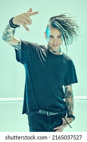 A handsome punk rock musician with dreadlocks in stylish black clothes  posing among neon lamps on a light background. Space punk rock music. Youth alternative culture.  - Shutterstock ID 2165037527