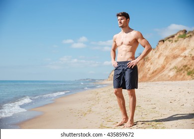 Handsome Relaxed Young Man In Black Shorts Standing On The Beach