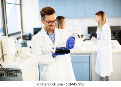 Handsome researcher in protective workwear standing in the laboratory and analyzing liquid samples - Powered by Shutterstock