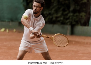 Handsome Retro Styled Tennis Player Hitting Ball At Tennis Court