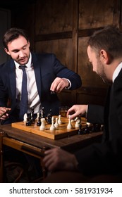 Handsome rich businessmen playing chess showing rivalry or competition between their business of companies, enterprises, firms. Business competition concept.