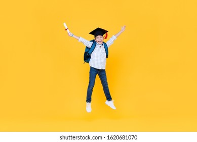 Handsome schoolboy with graduate cap smiling and jumping on yellow background for educatin concept - Powered by Shutterstock