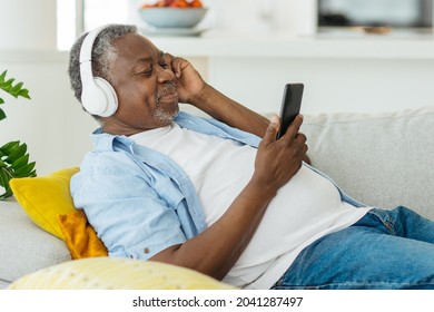 Handsome senior African man listening to the music and relaxing in his cozy apartment.