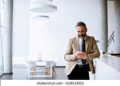 Handsome senior businessman using mobile phone in modern office - Powered by Shutterstock