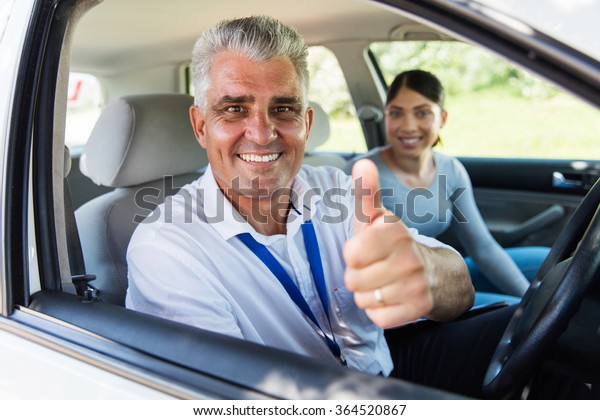 handsome senior\
driving instructor giving thumb\
up