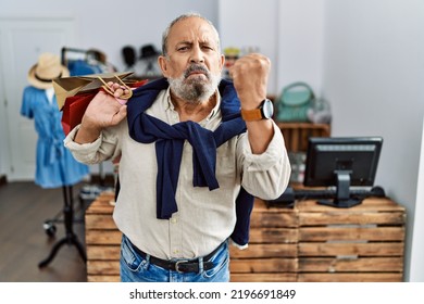 Handsome Senior Man Holding Shopping Bags At Boutique Shop Angry And Mad Raising Fist Frustrated And Furious While Shouting With Anger. Rage And Aggressive Concept. 