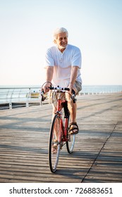 Handsome Senior Man Riding Bike On Seafront