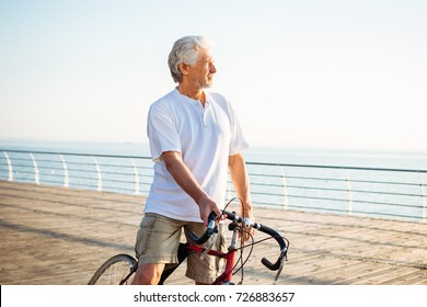 Handsome senior man riding bike on seafront - Powered by Shutterstock