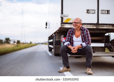 Handsome senior man sitting on the back side of his truck.