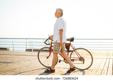 Handsome senior man walking with bike on seafront - Powered by Shutterstock