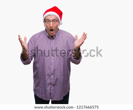 Handsome senior man wearing christmas hat over isolated background celebrating crazy and amazed for success with arms raised and open eyes screaming excited. Winner concept