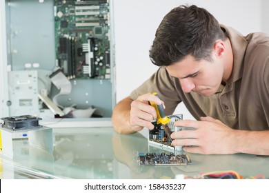 Handsome serious computer engineer repairing hardware with pliers in bright office