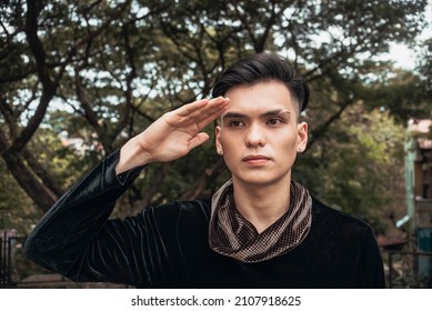 A Handsome And Serious Looking Man Makes A Military Salute, Apparently Looking At A Superior, While In Civilian Clothing.