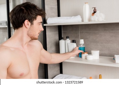 Handsome Shirtless Man Taking Mouthwash From Shelf In Bathroom