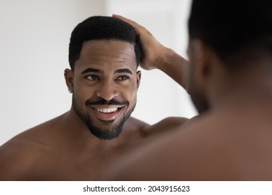 Handsome Shirtless Muscular Build African Man Standing In Bathroom Looking In Mirror Touch His Natural Afro Hair, Concept Of Happy Client Of Barber Shop Services, Haircare Treatment, Cosmetics For Men