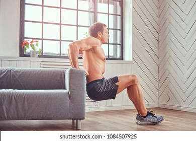 Handsome Shirtless Muscular Male Does Exercise Leaning On A Sofa At Home.