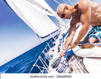 Handsome Shirtless Sailor Working On Sailboat, Pulling Rope On Crank, Summer Time Activity, Spending Vacation In A Sea Traveling
