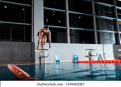 Handsome And Shirtless Swimmer Standing In Starting Pose On Diving Block