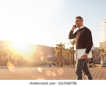 Handsome Silver Fox Man Talking On Mobile Phone Walking Outdoors At Sunset 