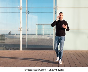 Handsome Silver Fox Man Talking On Mobile Phone With Glass Office Building In Background 