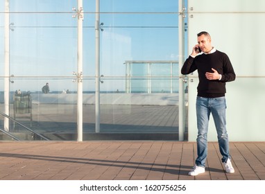 Handsome Silver Fox Man Talking On Mobile Phone With Glass Office Building In Background 