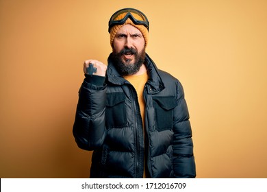 Handsome Skier Bald Man With Beard Skiing Wearing Snow Sportswear And Ski Goggles Angry And Mad Raising Fist Frustrated And Furious While Shouting With Anger. Rage And Aggressive Concept.