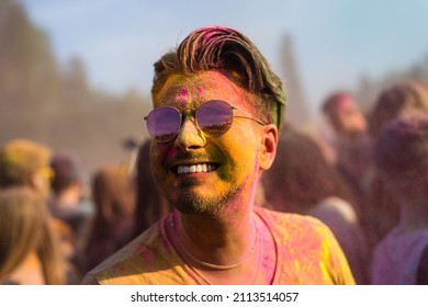 handsome smiling black hair man with colorful face having fun on Holi color festival