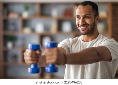 Handsome Smiling Black Man Exercising With Dumbbells At Home, Smiling Young African American Male Training In Living Room Interior, Enjoying Active Healthy Lifestyle, Closeup Shot With Copy Space